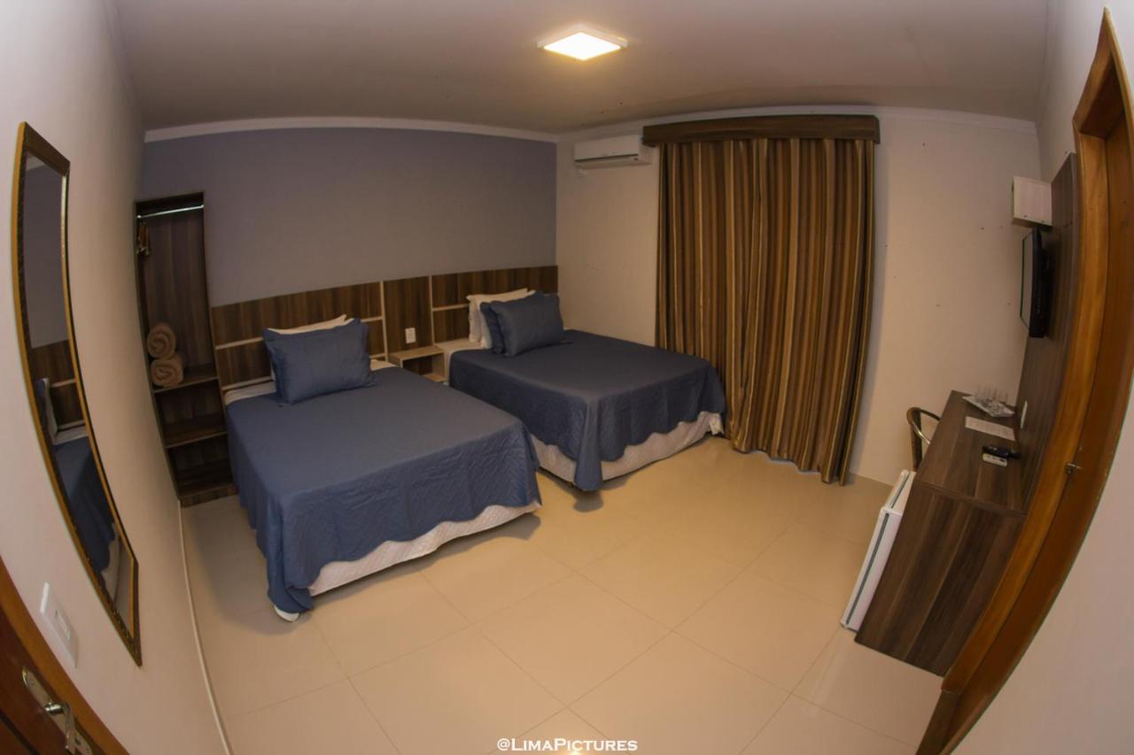Quarto com duas camas de solteiro e cabeceira de madeira